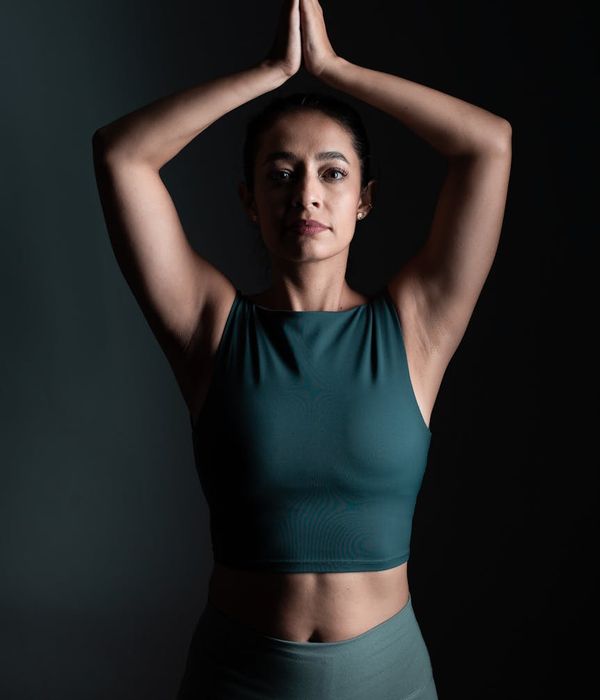 Woman in a calm yoga pose in a dark studio with red ambient light.